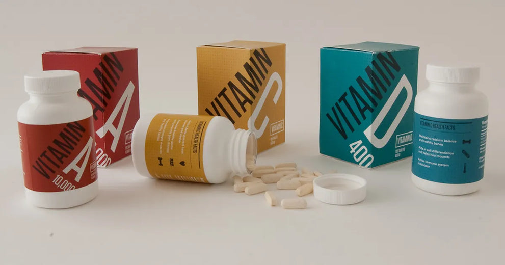 Amber supplement capsules beside a clear ingredient label and a glass of water on a bright table